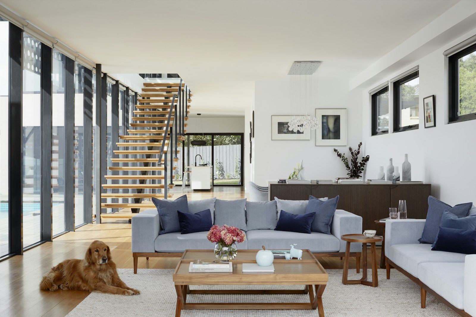Light-filled open living room with a timber stair and large glass doors.